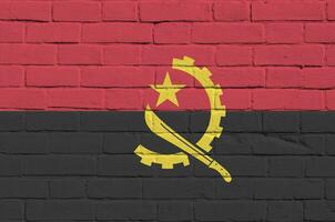 Angola vlag afgebeeld in verf kleuren Aan oud steen muur. getextureerde banier Aan groot steen muur metselwerk achtergrond foto