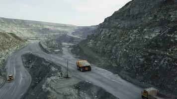 dump vrachtauto is Bij groeve. top visie van het rijden oranje dump vrachtauto met puin Aan weg Open pit. zwaar vervoer in mijnbouw industrie foto