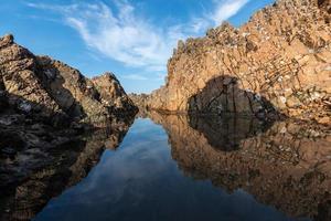 het zeewater tussen de kustriffen weerspiegelt de gele riffen en de blauwe lucht foto