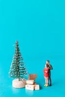 miniatuur mensen, verliefd stel naast een kerstboom foto