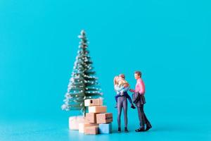 miniatuurmensen, gelukkige familie die naast een kerstboom staat foto