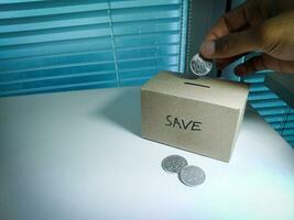 besparing geld met hand- zetten munten in een doos spaargeld foto