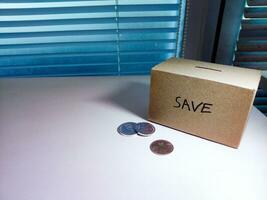 een doos van spaargeld en munten gestapeld Aan een tafel, voor achtergrond doel foto