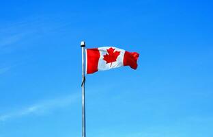 de vlag van Canada Aan blauw lucht achtergrond dichtbij omhoog. foto