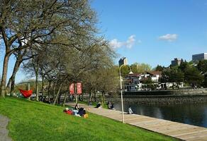 mensen genieten van een zonnig voorjaar dag in de buurt de water in de park, met een verbijsterend stadsgezicht in de achtergrond. Vancouver, v.Chr., Canada. mei 02, 2021. foto