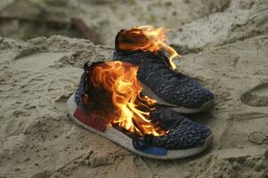 gebruikt blauw sportschoenen brandend Aan een zand in de Woud. foto