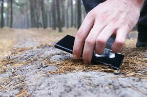 vinden een smartphone Aan een Woud pad. foto