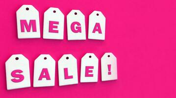 negen wit houten tags met de woord mega uitverkoop Aan een roze achtergrond. foto