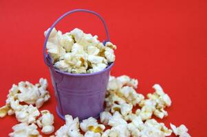 de vers popcorn in een klein decoratief ijzer emmer Aan een rood achtergrond. foto