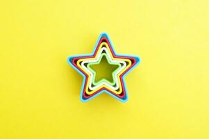 plastic mallen van multi kleuren voor maken koekjes in de vorm van een ster Aan een geel achtergrond. foto