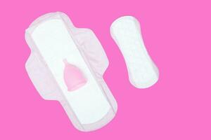 menstruatie- kopje, normaal vrouwelijk stootkussen en panty voering Aan roze achtergrond, boven visie. nul verspilling concept. milieuvriendelijk menstruatie- producten foto