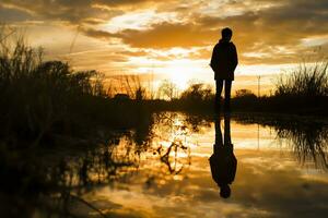 ai gegenereerd een reflecterende fotografie Bij zonsopkomst vastleggen silhouet tegen een gouden lucht foto