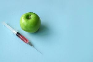 groen appel en injectiespuit met ggo Aan een blauw achtergrond. foto