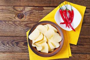 Aardappelchips, hete chili peper, gele servet op houten tafel achtergrond, mock up foto