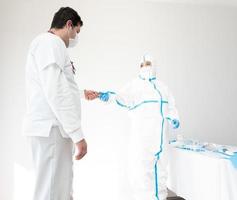 arts in beschermend kostuum werken in medische kamer met collega