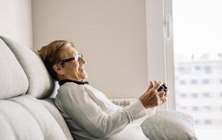 tevreden oudere vrouw met console die videogame speelt foto