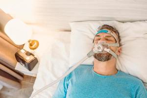 slapende man met chronische ademhalingsproblemen overweegt cpap-machine in bed te gebruiken. gezondheidszorg, obstructieve slaapapneu-therapie, cpap, snurkconcept foto