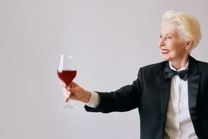 stijlvolle senior sommelier vrouw in smoking met glas of rode wijn. drank, volwassen, stijlconcept foto