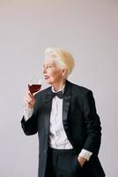 stijlvolle senior sommelier vrouw in smoking met glas of rode wijn. drank, volwassen, stijlconcept foto