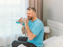 gelukkig uitgeslapen man met chronische ademhalingsproblemen na het gebruik van een cpap-machine zittend op het bed in de slaapkamer. gezondheidszorg, cpap, obstructieve slaapapneu-therapie, snurkconcept foto