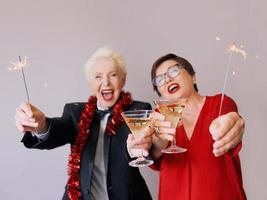 twee mooie stijlvolle volwassen senior vrouwen die nieuwjaar vieren. plezier, feest, stijl, feestconcept foto