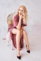 stijlvolle mooie blonde vrouw zit in haar boudoir in fluwelen gewaad. schoonheid, mode, stijl, huisconcept foto