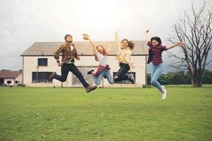 succesvolle jonge studenten op de campus kijken naar de camera en glimlachen en high five terwijl ze buiten springen. foto