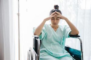 Aziatische vrouwenpatiënt op rolstoel en ze heeft hoofdpijn in een ziekenhuis