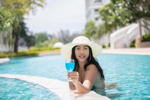 vrouwen dragen bikini's en drinken cocktails in de hete zomer bij het zwembad. foto