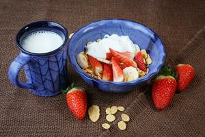 gezond ontbijt. cornflakes, vers aardbeien, banaan, yoghurt en melk foto