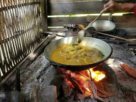 de werkwijze van Koken rendang of rundvlees en kip kerrie gebruik makend van de traditioneel methode, Koken gebruik makend van brandhout foto