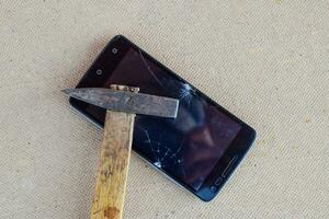 hamer en smartphone. de scherm van de smartphone, een gebroken ha foto