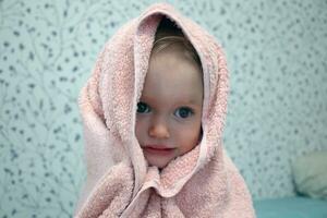 een weinig meisje is verpakt in een handdoek na baden. detailopname portret. foto