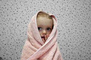 een weinig meisje is verpakt in een handdoek na baden. detailopname portret. foto