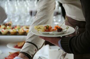 man's hand- met een bord van voorgerechten Bij de catering tafel foto