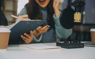 vrouw opname een podcast Aan haar laptop computer met hoofdtelefoons en een microscoop. vrouw podcaster maken audio podcast van haar huis studio. foto