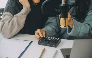 vrouw opname een podcast Aan haar laptop computer met hoofdtelefoons en een microscoop. vrouw podcaster maken audio podcast van haar huis studio. foto