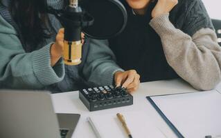 vrouw opname een podcast Aan haar laptop computer met hoofdtelefoons en een microscoop. vrouw podcaster maken audio podcast van haar huis studio. foto