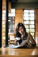 mooie vrouw die tijdschrift leest in café