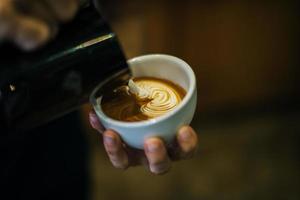 close-up van handen barista maakt latte koffie kunst verf