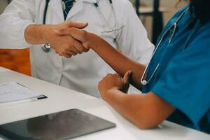 dokter en geduldig beven handen in de kantoor, ze zijn zittend Bij bureau, handen dichtbij omhoog foto