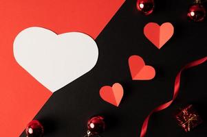 witte harten en rode harten van papier worden op een zwarte achtergrond geplaatst. foto