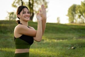 de concept van meester klassen en zaden. meisje glimlachen Bij de camera het uitvoeren van yoga opdrachten Aan de achtergrond van zomer natuur foto