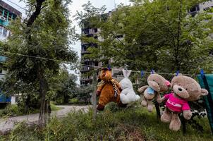 kinderen speelgoed hangen Aan een touw tegen de achtergrond van vernietigd verbrand huizen in Oekraïne foto