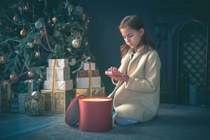 schattig meisje opening Cadeau De volgende naar Kerstmis boom. foto