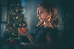 een schattig meisje in een zwart jurk zit Bij een tafel met mandarijn. vakantie, nieuw jaar, Kerstmis foto