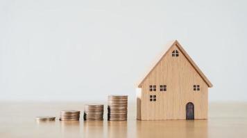 houten huis en stapelen van munten op houten tafel. geld besparen voor het kopen van een huis, financieel plan voor woningkrediet. foto