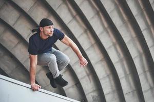 jonge man doet parkour sprong in stedelijke ruimte in de stad zonnige lente zomerdag. foto