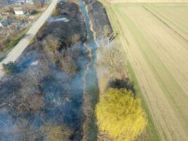 brandend droog gras langs de irrigatie kanaal. rook en de vlam van droog gras. verbrand droog gras. foto