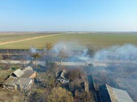 brandend van droog gras Aan de buitenwijken van de dorp. foto